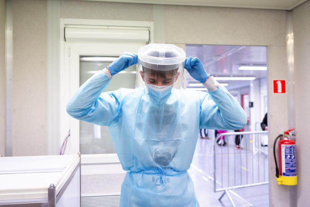 A nurse working at the Belgian Red Cross COVID-19 testing center in Etterbeek. She is fully dressed in her protective uniform and is also wearing blue gloves.
