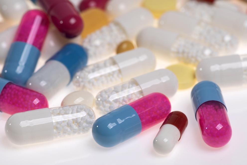 Pillen in verschiedenen Farben (rot, rosa, blau, weiß, gelb, durchsichtig) liegen auf einem Haufen übereinander.